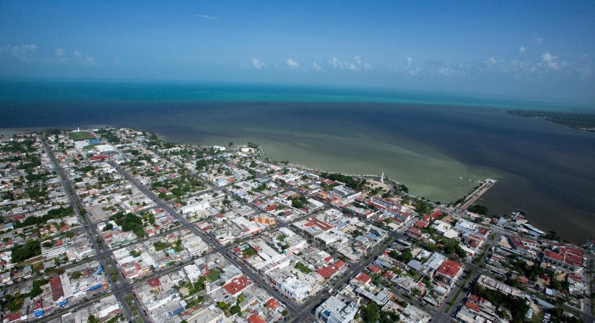 Vista aérea de Chetumal con sus zonas residenciales, comerciales y la bahía al fondo bajo cielo despejado.