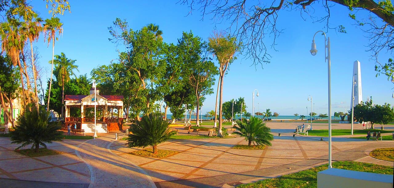 Parque costero con malecón, áreas verdes, kiosco y vista al mar en una zona turística de Quintana Roo.