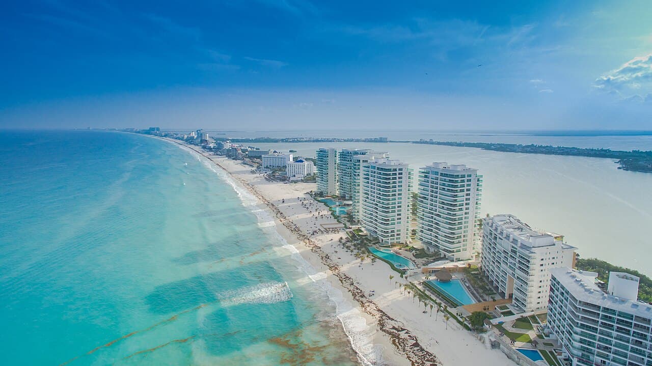 Vista aérea de complejos hoteleros de alta ocupación frente a playa turquesa en la Riviera Maya, Quintana Roo.